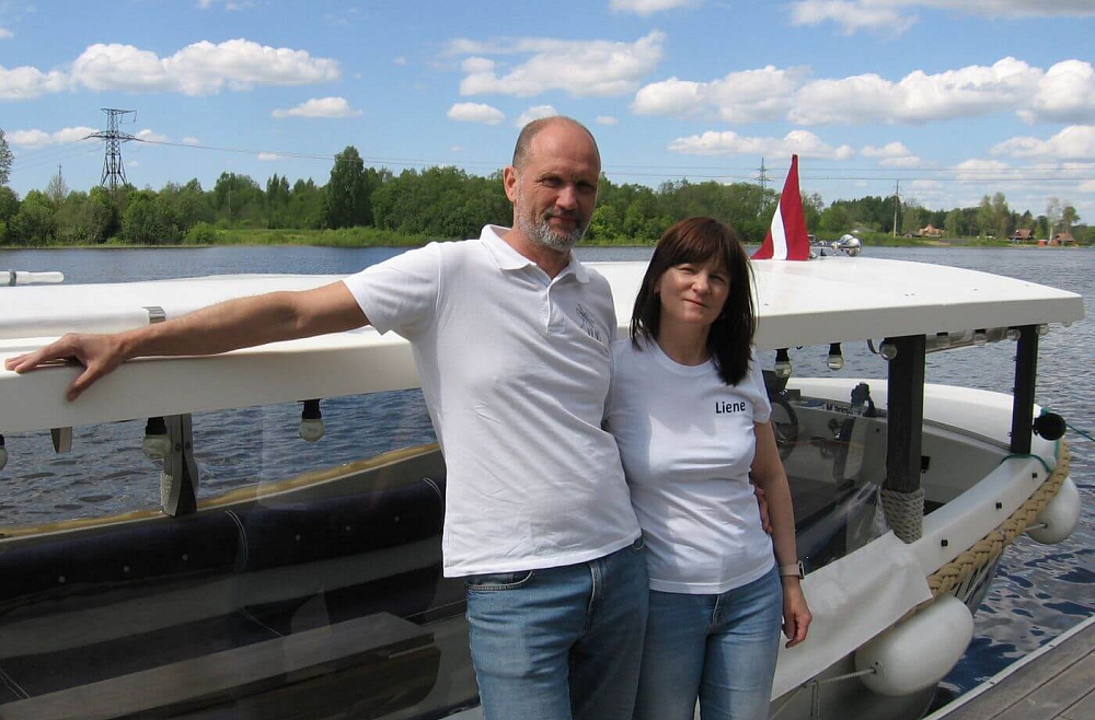 Vilnis un Liene Vecmaņi tūristus ar kuģīti vizina pa Cieceres ezeru un cienā ar kūkām